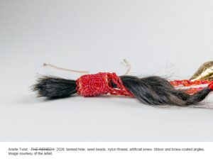 A red beaded band wrapped around dark braided hair.