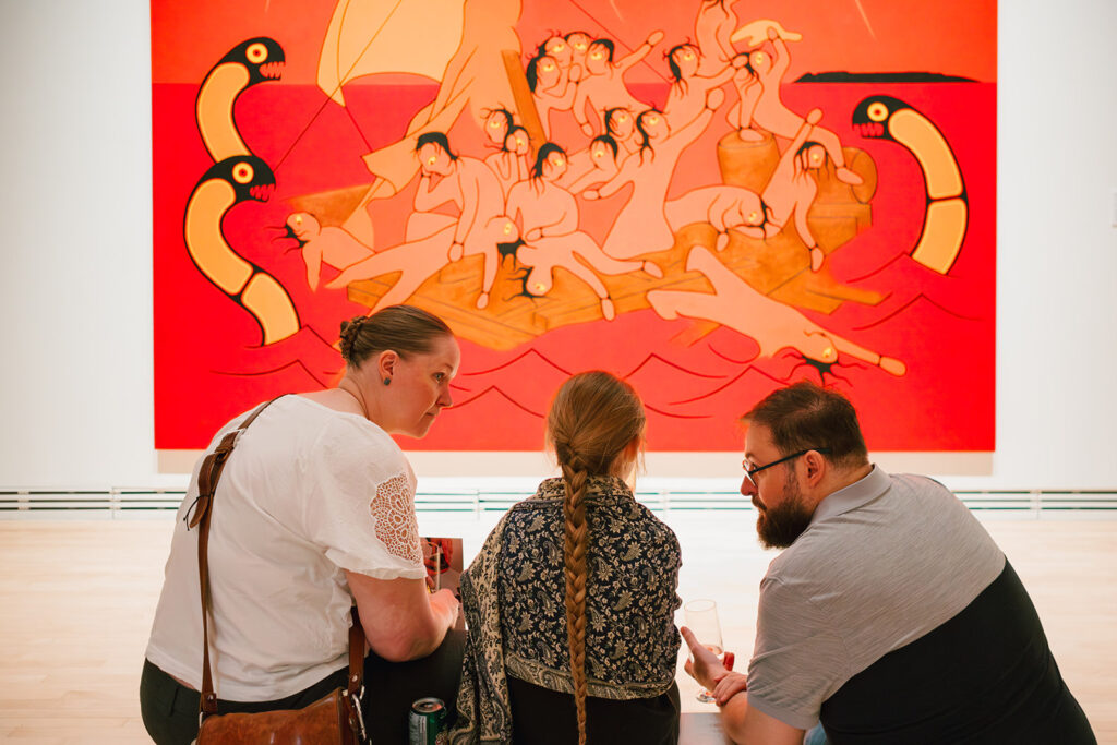 A family takes in a large painting from the Runs in the Family Exhibition